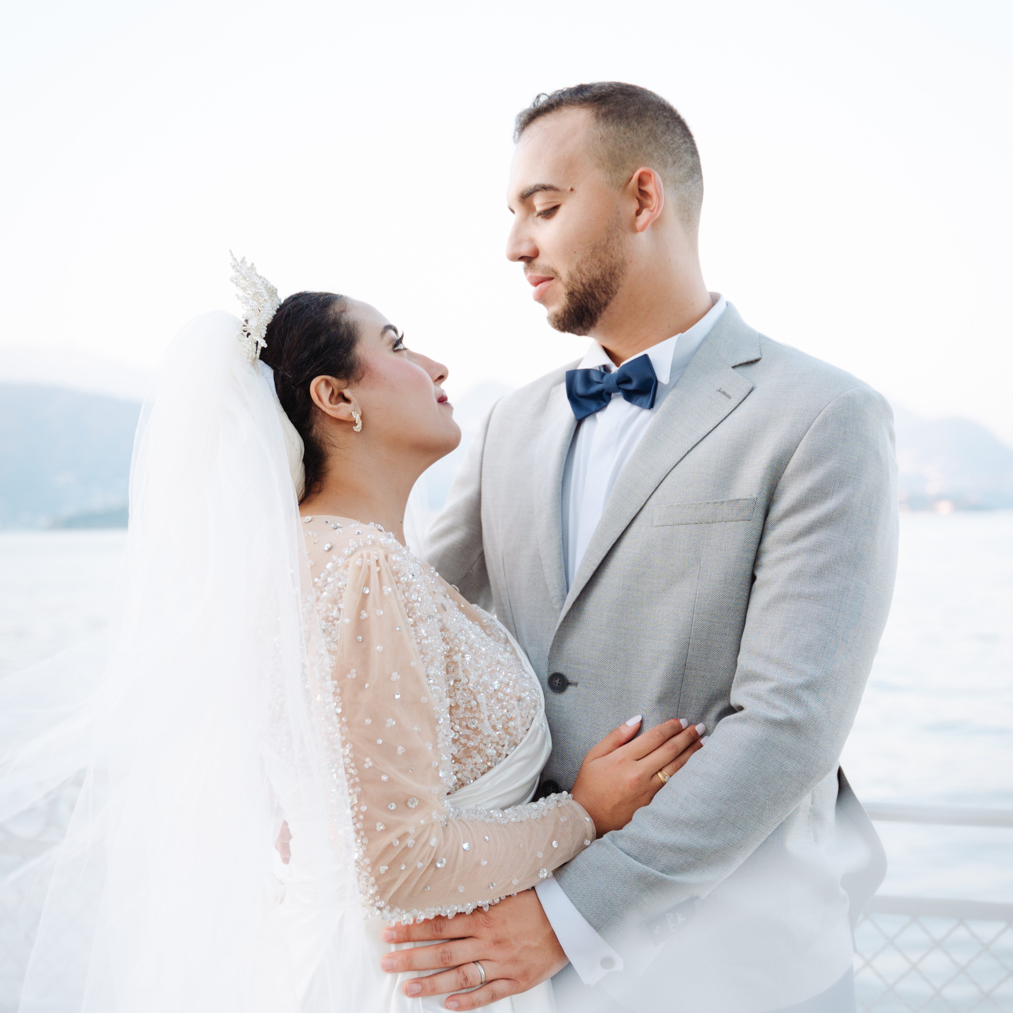 Bride and groom posing with Lake Maggiore in the backround. They are looking into each other's eyes while hugging