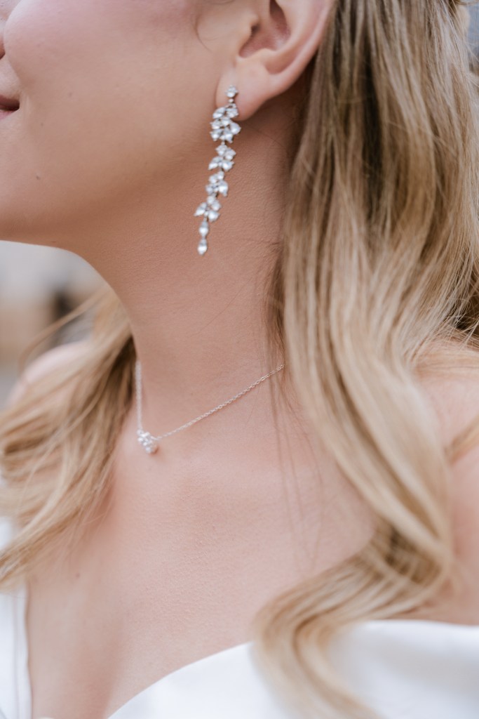 Detail shot of the bridal look focusing on her jewelry: the long earrings and a delicate necklace