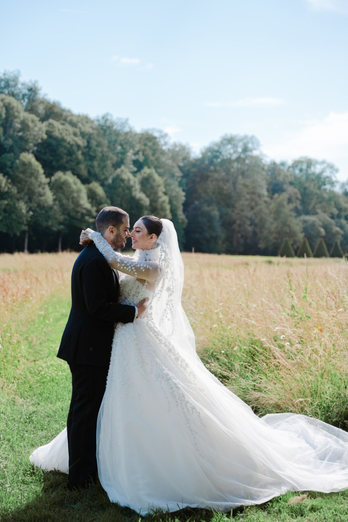 Bride and groom are posing in the middle of a green field in France