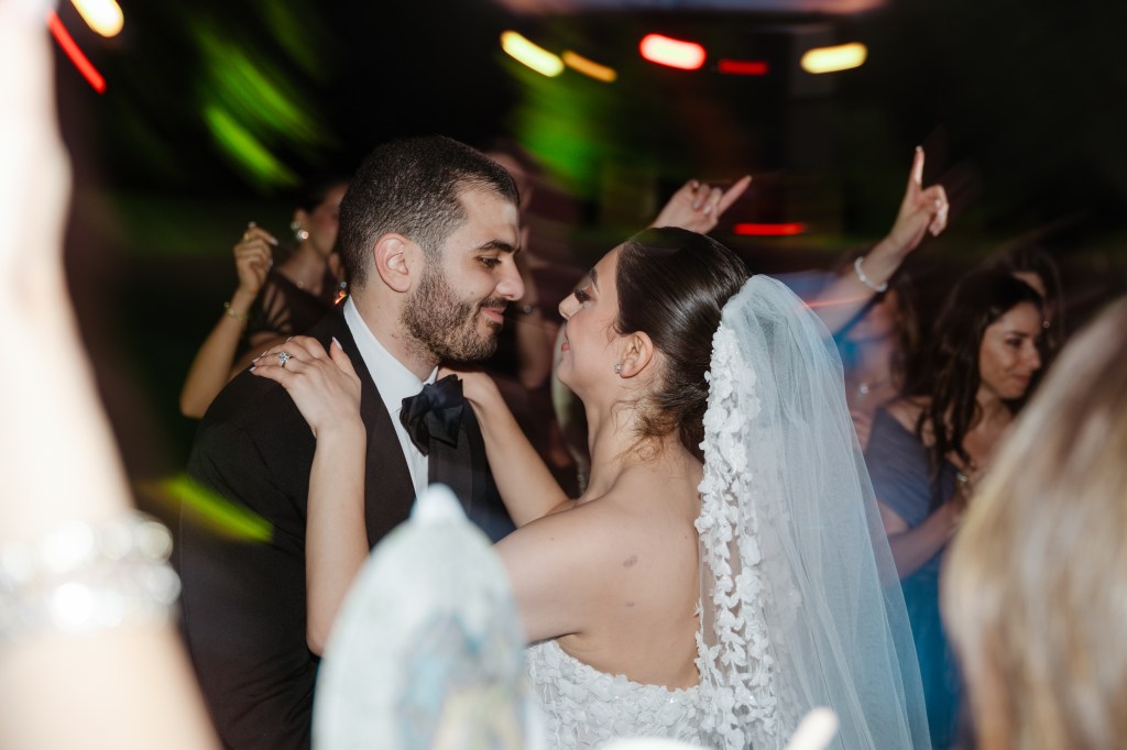 A dynamic photo of bride and groom dancing together in the middle of the guest croud.