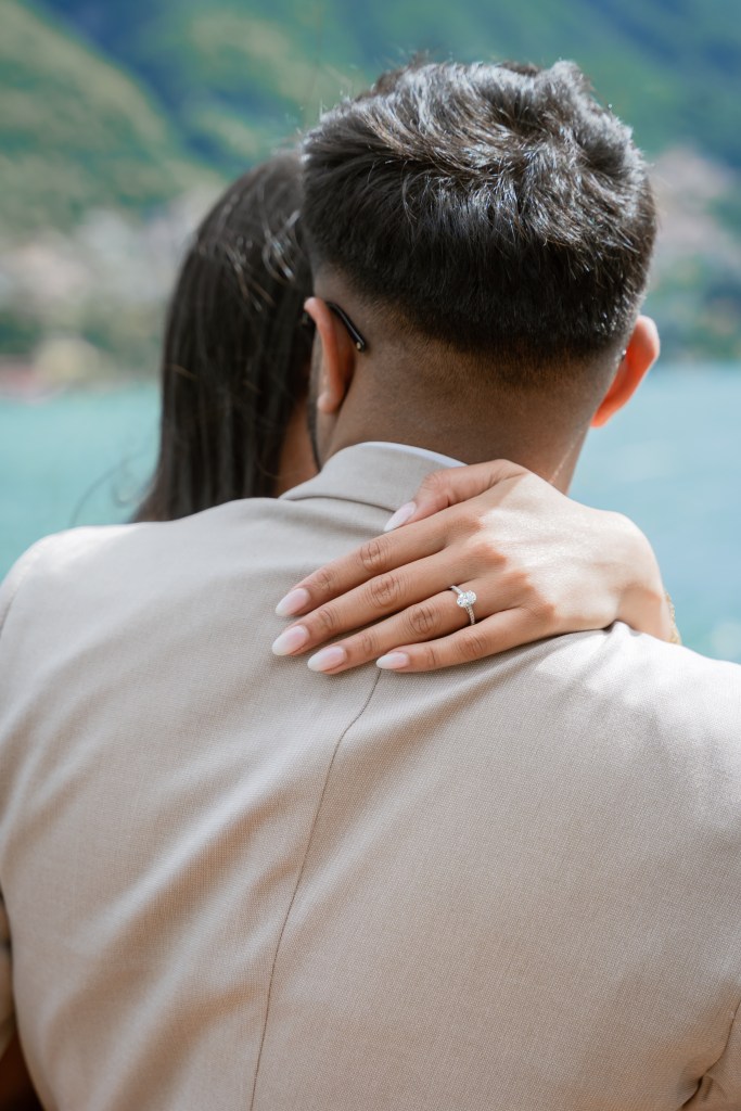 A close up shot of an engagement ring while the future bride had her hand around the fiance's shoulder
